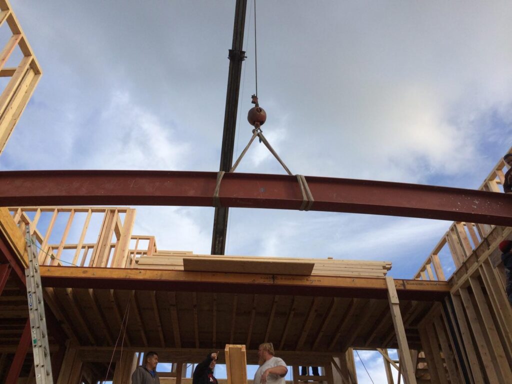 Steel beam on the hook over a framed house