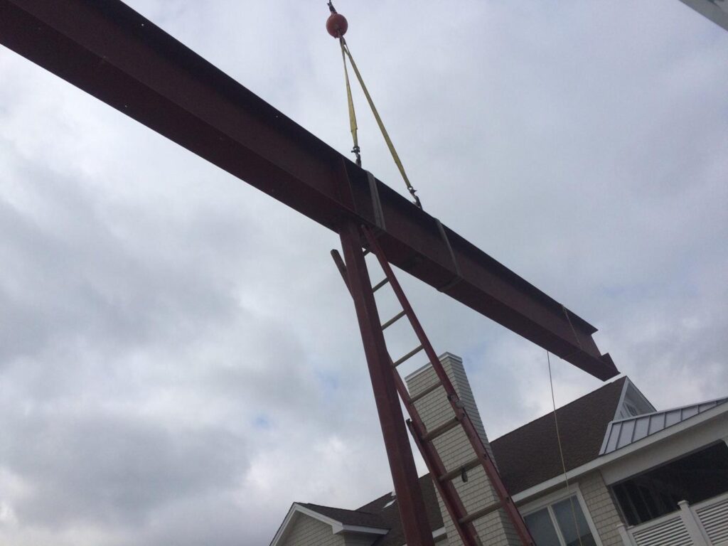 Steel beam on the hook over a framed house