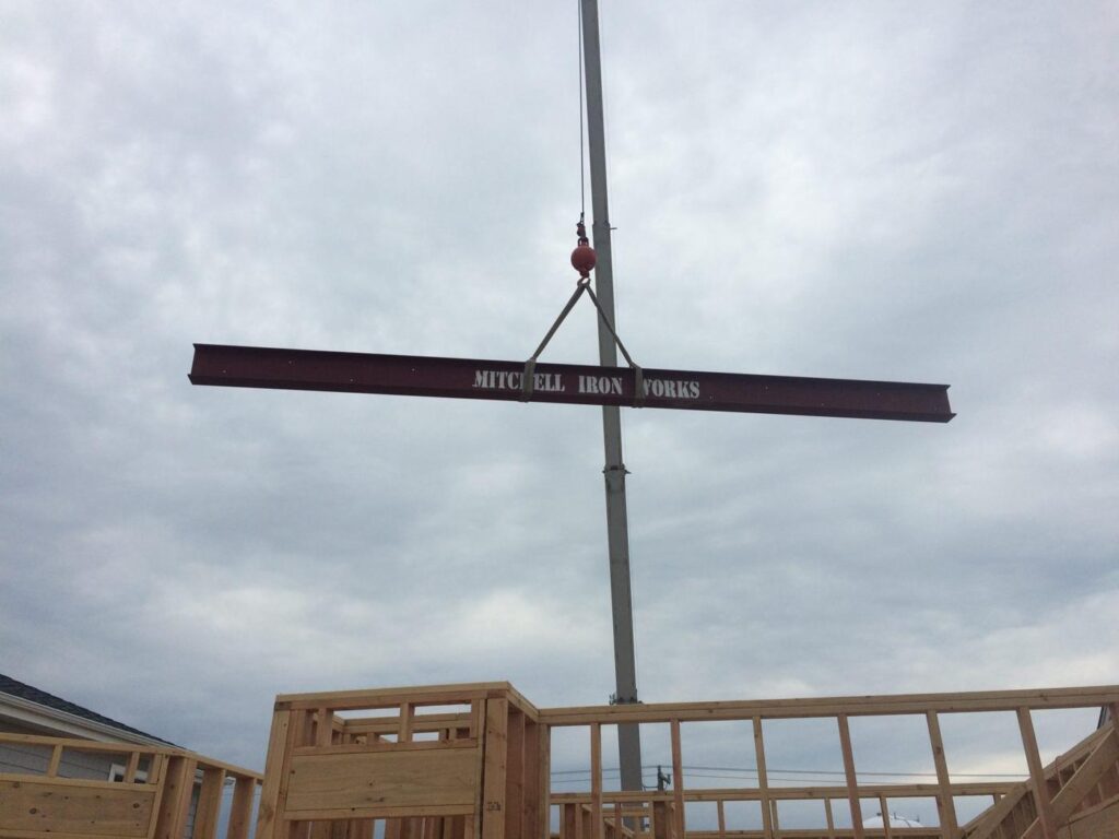 Steel beam on the hook over a framed house