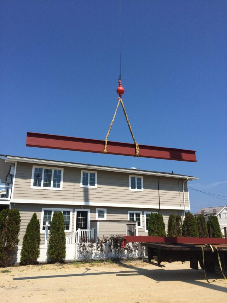 Steel beam on the hook over a framed house