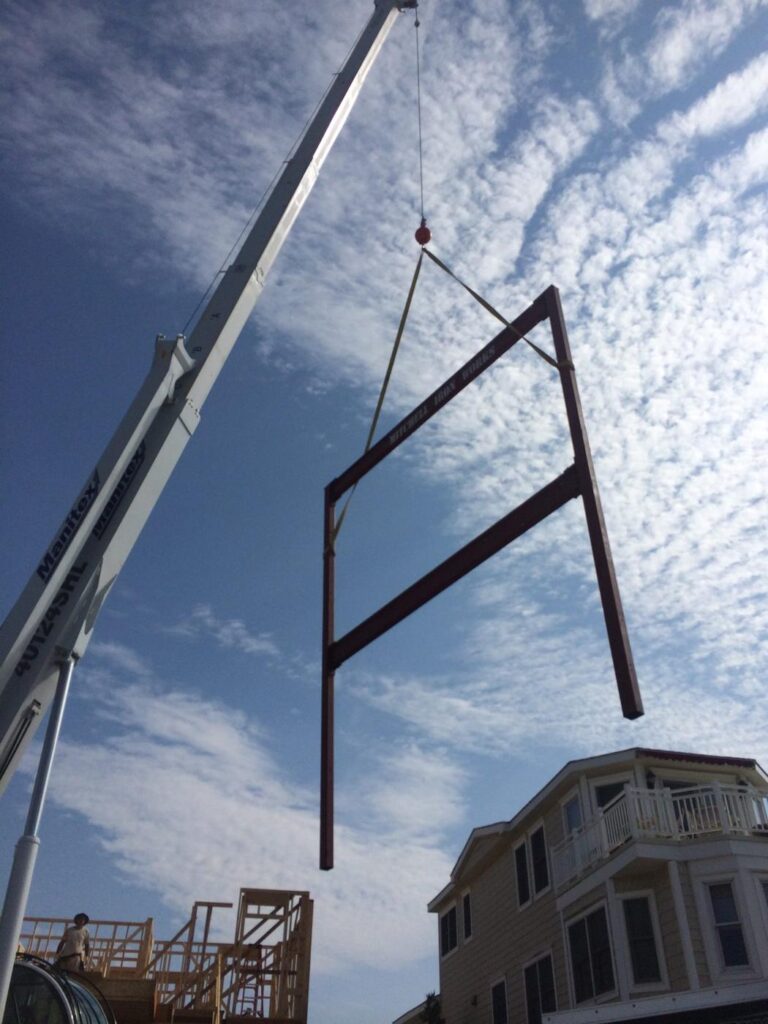 Steel beam on the hook over a framed house