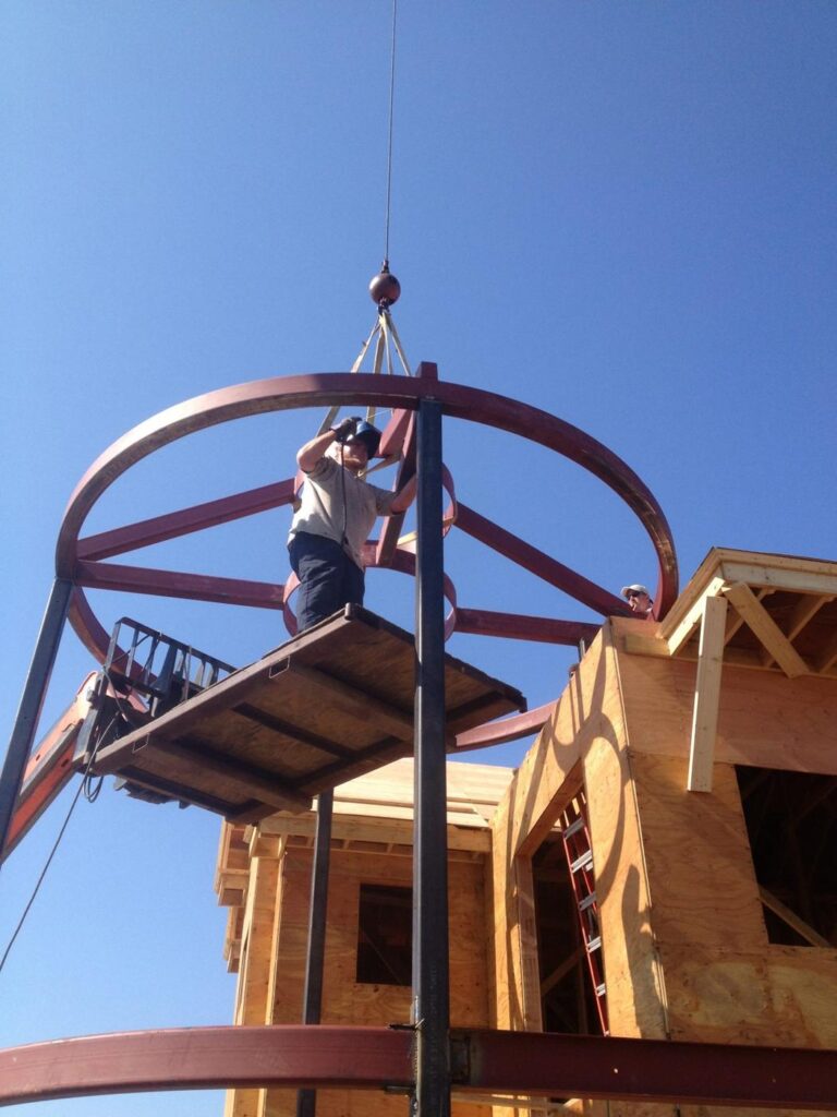 Round steel turret frame lifted into place by crane