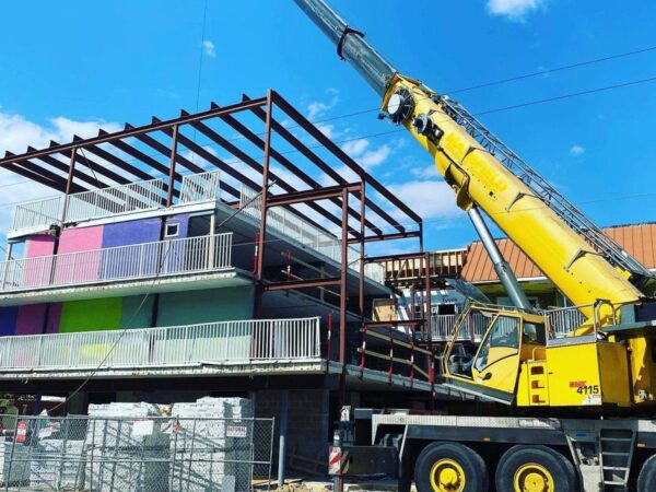 Grove GMK4115 setting steel framing on top of a shore motel